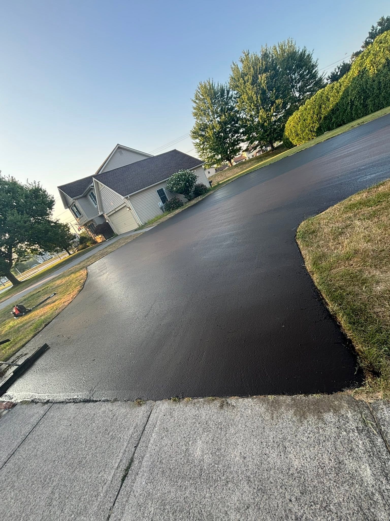 Professional driveway sealcoating result showing deep black finish on a Monroe County NY home